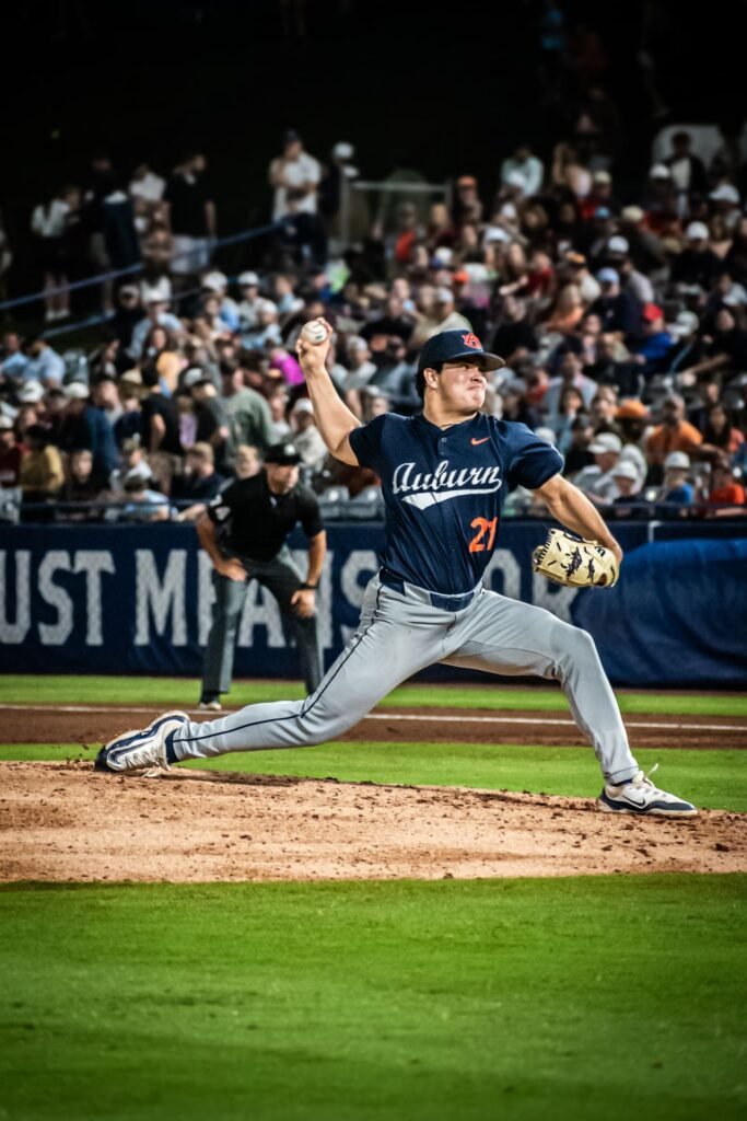 Pitcher in a navy jersey following through on a pitch