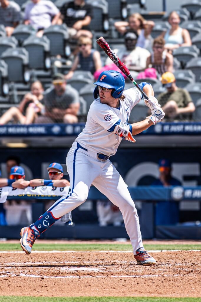 Batter in a white jersey swinging at a pitch