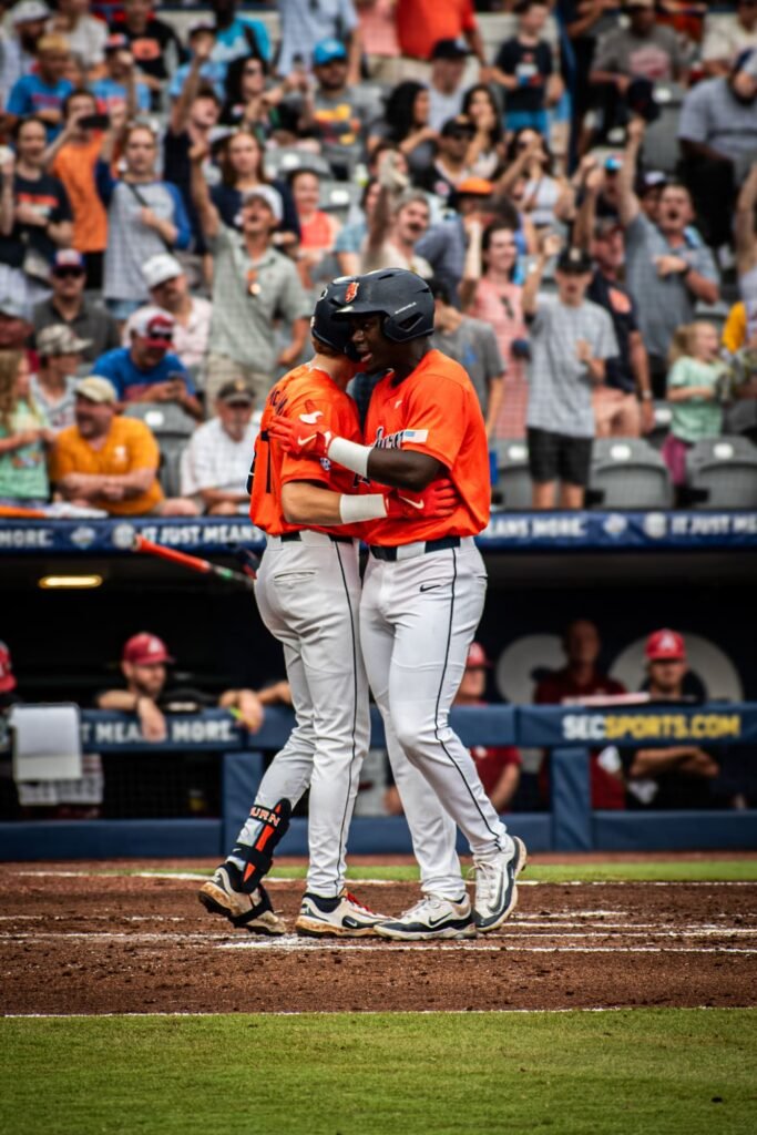 Two players in orange hugging at home plate after a home run