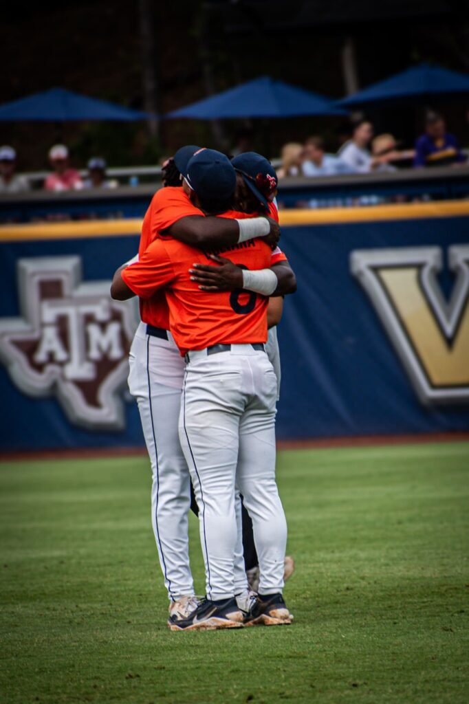 Two teammates in orange embracing on the field