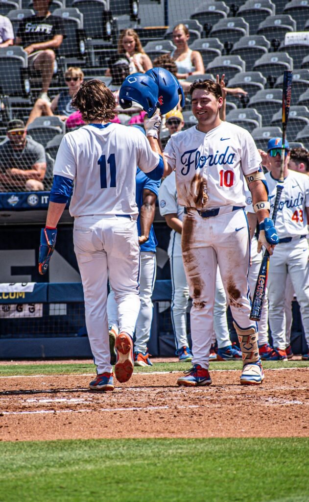 Players in white uniforms celebrating at the plate