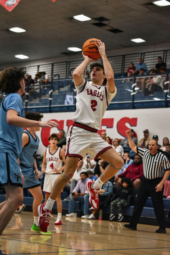 Player in white and red rising for a jump shot over defenders