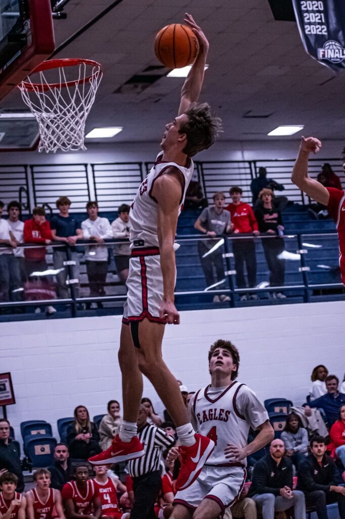 Player dunking with both hands as the crowd watches