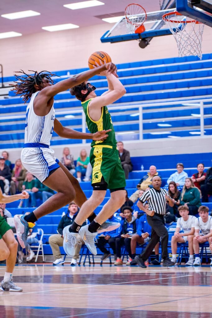 Player in white driving to the basket past a defender in green