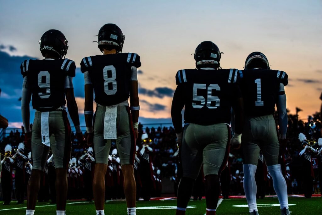 Two players, numbers 8 and 56, standing side by side facing the field at dusk