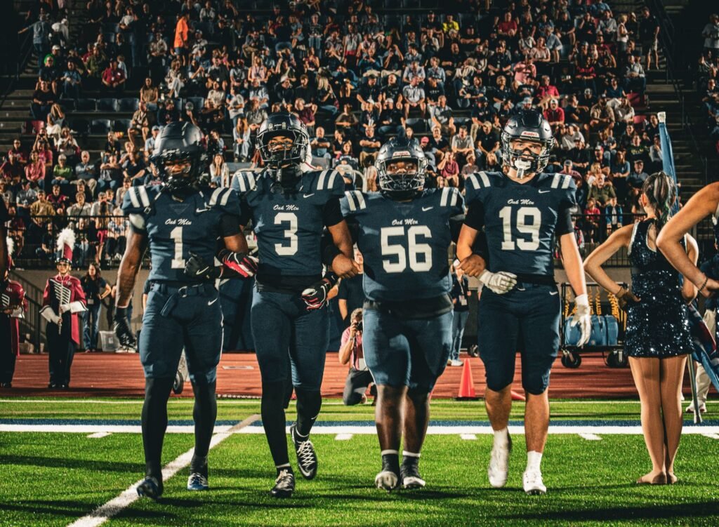 Team in navy jerseys walking out arm in arm in front of a packed stand