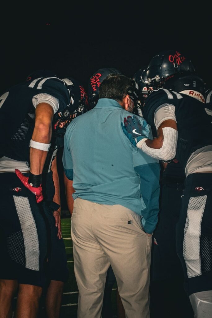 Coach in a blue shirt in the middle of a team huddle
