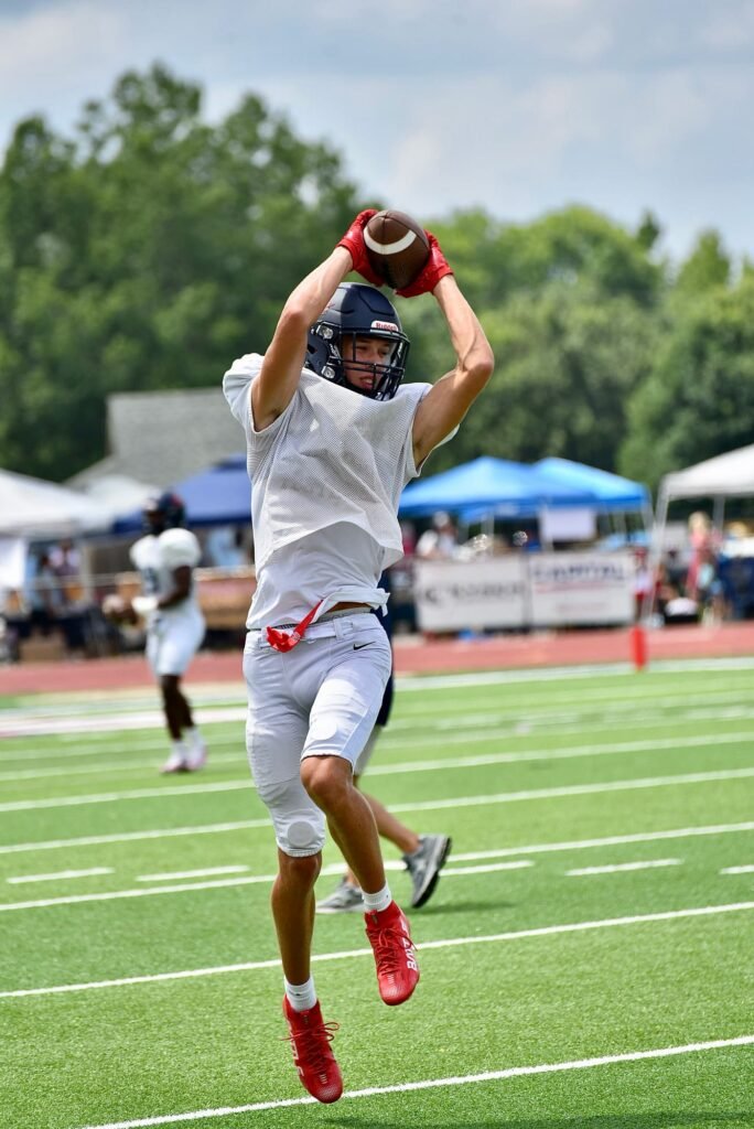 Receiver in white pulling in a catch in a daytime game
