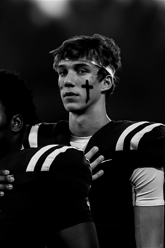 Black-and-white photo of a player with a cross painted under his eye