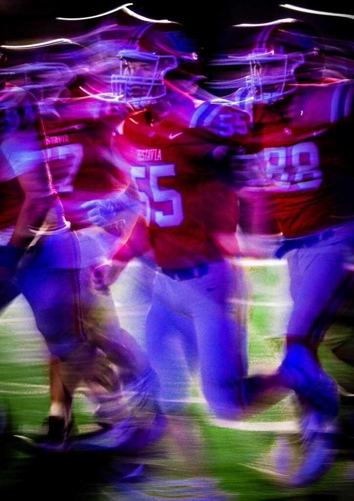 Motion-blurred football players under stadium lights