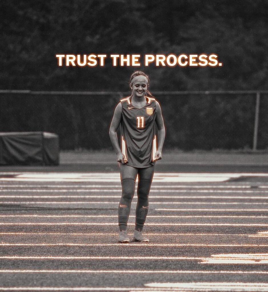 Soccer player in a number 11 kit walking off the field, "trust the process" written above her